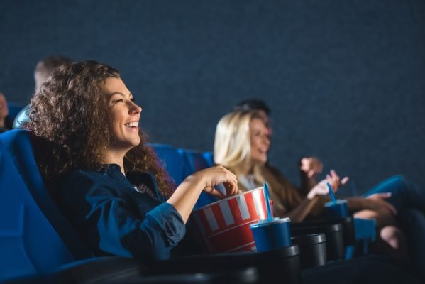 side-view-of-cheerful-woman-with-popcorn-watching-movie-in-cinema.jpg